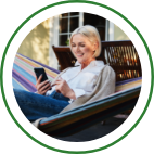 A woman scrolls through her mobile phone while sitting in an outdoor hammock. 